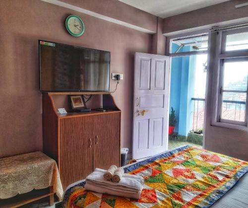 1 dormitorio con 1 cama y TV de pantalla plana en Mysa Maya Homestay, en Darjeeling