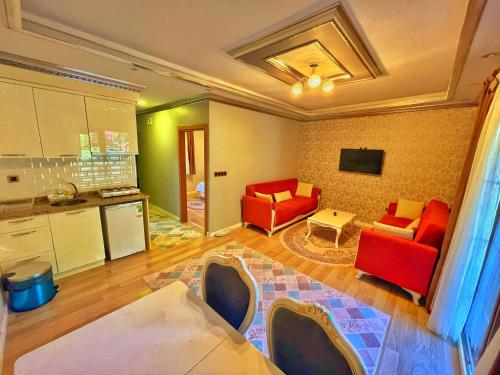 a living room with two red chairs and a kitchen at Kuzey Suite Otel in Uzungöl