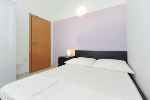 a bedroom with a white bed and a wooden door at Apartmani Dragičević in Vir