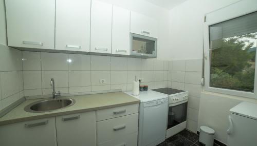 a white kitchen with a sink and a window at Flamingo in Virpazar
