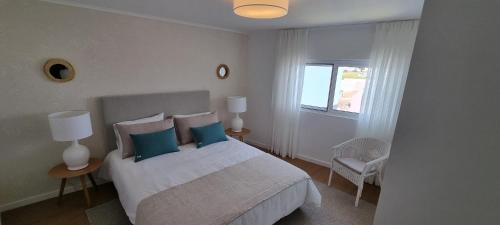 a bedroom with a bed with blue pillows and a window at Sea House - Santa Clara in Ponta Delgada