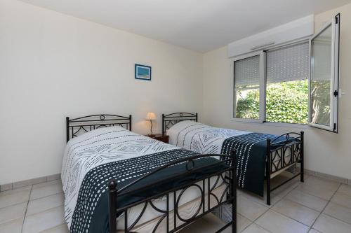 two twin beds in a room with a window at Care Villa T4 avec piscine in Moliets-et-Maa