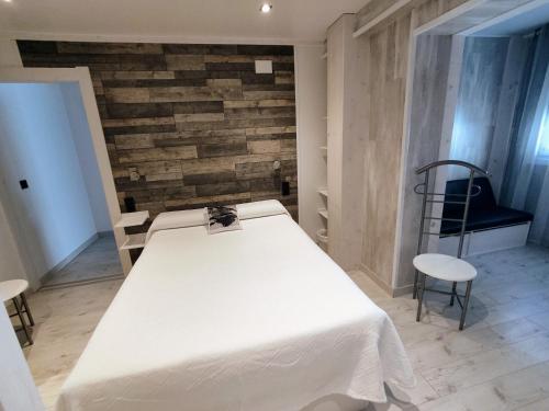 a bedroom with a white bed and a brick wall at Alojamiento Txokoto in Elizondo