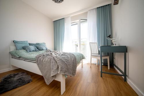 a bedroom with a bed and a desk and a window at Apartament Willa Lniana in Sulechów