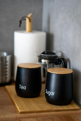 two black cups sitting on a wooden cutting board at Apartament Willa Lniana in Sulechów