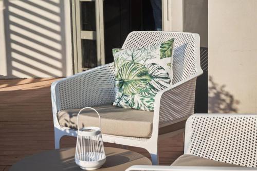 a white wicker chair with a pillow on a porch at 7Rizes Luxury Living in Heraklio Town