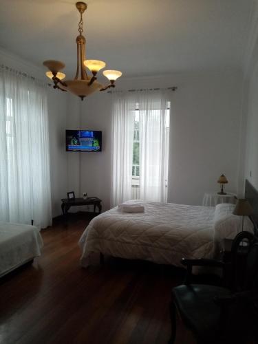a bedroom with two beds and a chandelier at Nossa Casa na Aldeia in Viseu