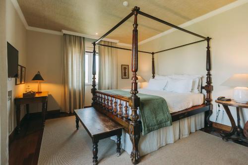 ein Schlafzimmer mit einem Himmelbett und einem Tisch in der Unterkunft Casa das Pipas / Quinta do Portal in Sabrosa