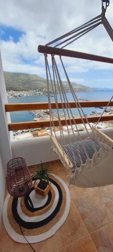 a balcony with a hammock and a view of the ocean at Spongia Apartments Kalymnos in Kalymnos