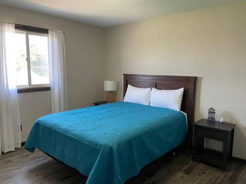 Schlafzimmer mit einem Bett mit blauer Bettdecke und einem Fenster in der Unterkunft 3 Bedroom Condo with Lake Pepin views with access to shared outdoor pool in Lake City