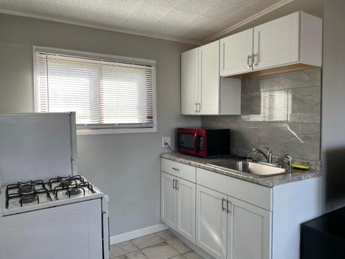 Una cocina con gabinetes blancos, un fregadero y un microondas. en 2 Bedroom Suite with kitchen, en Lake City