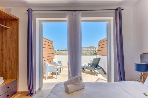 フロリアーナにあるTritoni Valletta Boutique Hotelのベッドルーム1室(ベッド1台付)、パティオ付きのガラスのスライドドアが備わります。