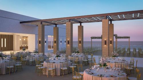 a banquet hall with tables and chairs and the ocean at Royalton Splash Riviera Cancun, An Autograph Collection All-Inclusive Resort in Cancún
