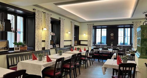 un restaurante con mesas y sillas blancas y ventanas en Hotel Neuhauser, en Volkach