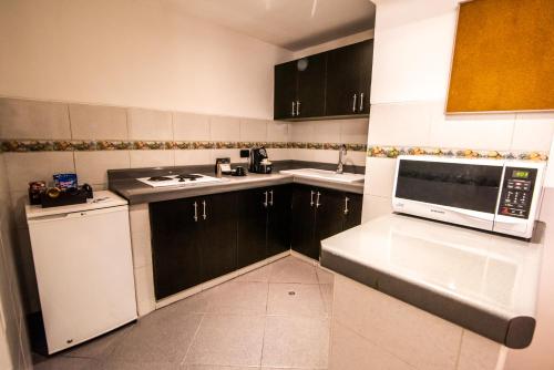 a kitchen with black cabinets and a white microwave at El Polo Hotel & Suites in Lima