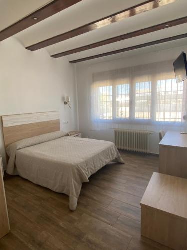 a bedroom with a bed and two windows at HOSTAL RESTAURANTE SAN ISIDRO in Quintanar de la Orden