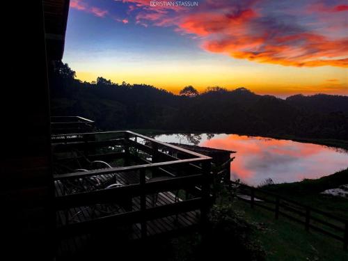 a sunset over a body of water with a fence at Pousada Rio Túnel in Aiuré