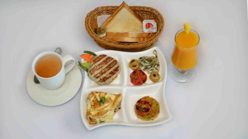 a plate of breakfast food and a cup of tea at Hotel Shaheen Continental Multan in Multan