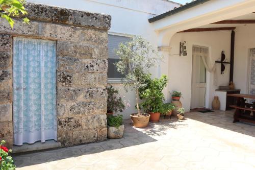 un muro in pietra con piante in vaso in un cortile di Masseria Salentina a Marina Serra