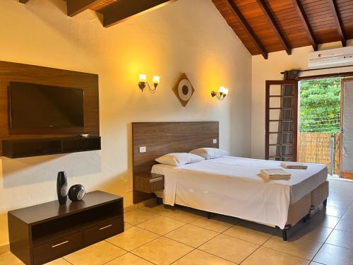 a bedroom with a bed and a flat screen tv at Delphin Apartamento 7 in Ilhabela