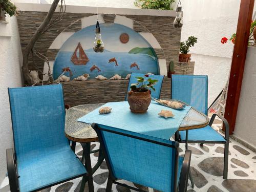 een tafel met twee blauwe stoelen en een vaas erop bij Pelagos in Aiyiáli