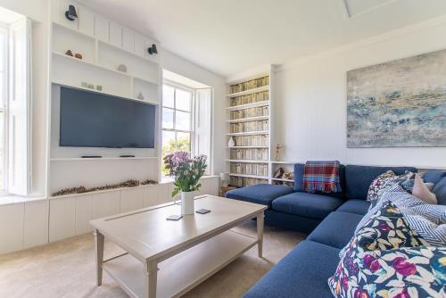 a living room with a blue couch and a tv at Primrose Cottage in St Ives