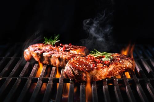 two pieces of meat on a grill with flames at Royalton Splash Riviera Cancun, An Autograph Collection All-Inclusive Resort in Cancún