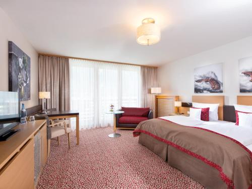 a hotel room with a large bed and a desk at aja Fürstenhaus am Achensee in Pertisau
