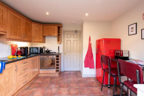a kitchen with a red refrigerator and wooden cabinets at 3 Bedroom House - a very British place to stay - near city centre ! in Oxford