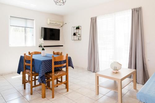 a dining room with a table and chairs and a tv at Alexandros Luxury Apartments Nydri in Nydri