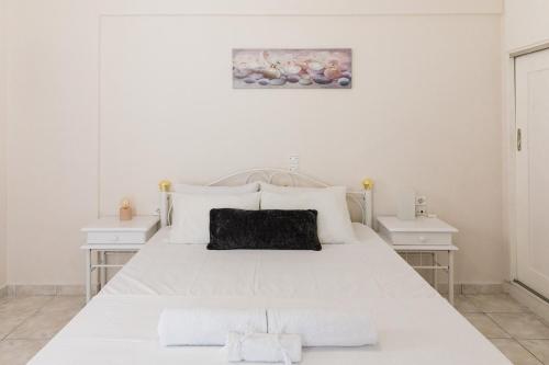 a white bedroom with a large white bed with two night stands at Alexandros Luxury Apartments Nydri in Nydri
