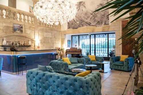 a living room with blue couches and a chandelier at Le Confidentiel Hôtel & SPA in Saint-Raphaël