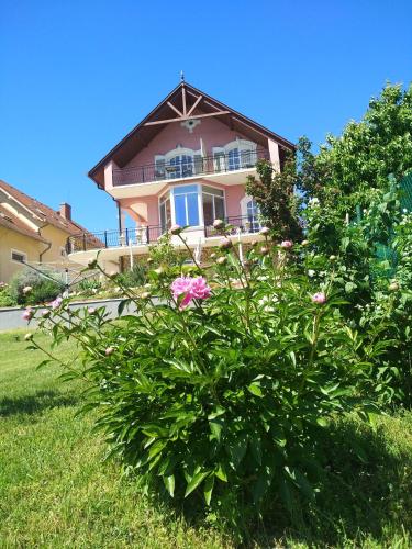 a pink house with a flower bush in front of it at Manor Villa in Hévíz