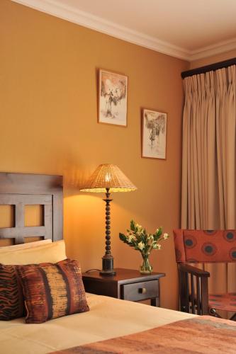 a bedroom with a bed and a lamp and a chair at Claires of Sandton Luxury Guest House in Johannesburg