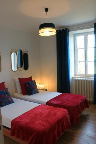 a bedroom with two beds with red sheets and a window at Le gîte de la glycine in Palmas