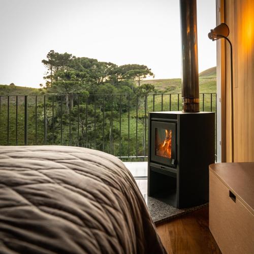 a bedroom with a fireplace in front of a window at Refúgio Casa de Pedra in Cambará