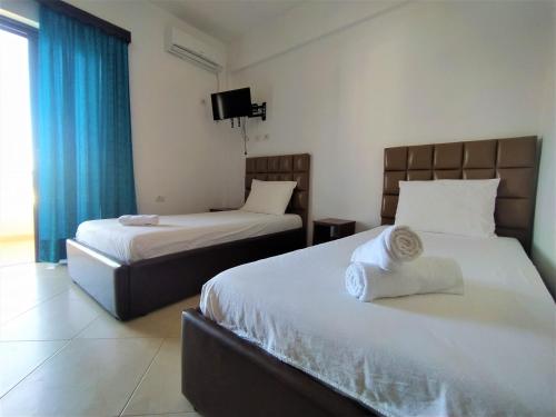 a hotel room with two beds and a television at Ahmeti Rooms in Ksamil