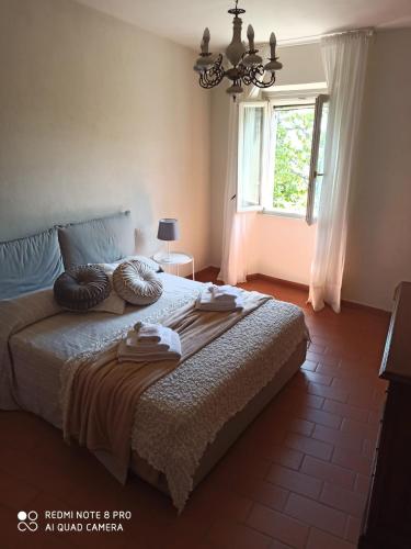 a bedroom with a bed with a chandelier and a window at Dépendance in Villa Albachiara in Carmignano