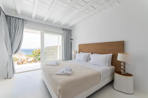 een witte slaapkamer met een groot bed en een groot raam bij Villa Leda Mykonos in Mykonos-stad