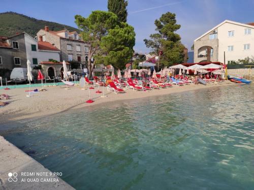 a beach with lounge chairs and umbrellas and the water at Mio Lux in Baošići