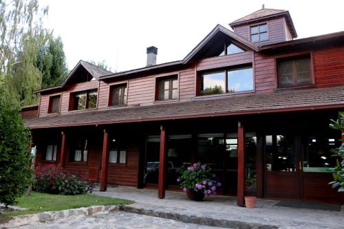 un grand bâtiment en bois avec des fleurs devant lui dans l'établissement Rincón de los Andes Resort, à San Martín de los Andes