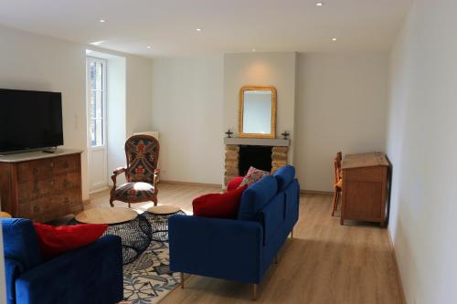 a living room with blue couches and a tv at Le gîte de la glycine in Palmas