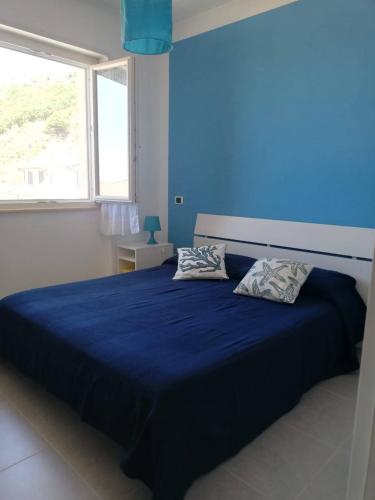 een blauwe slaapkamer met een groot bed met 2 kussens bij CASA BELLAVISTA in Nicotera