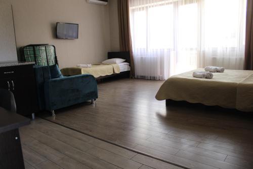 a hotel room with two beds and a blue chair at Hotel Rabati in Akhaltsikhe