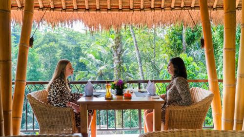 two women sitting at a table in a restaurant at Keliki Luxury Lodge in Ubud