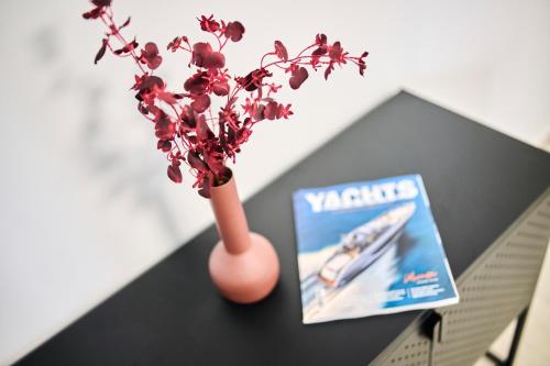 a vase with flowers on a table next to a magazine at Apartments Dolcea in Umag