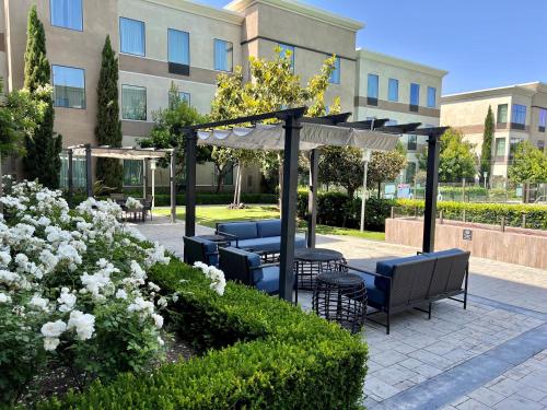 a patio with chairs and umbrellas in front of a building at Staybridge Suites Carlsbad/San Diego by IHG in Carlsbad