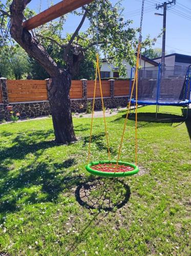 a swing set in a yard next to a tree at Apartmány Karolin in Uhorská Ves