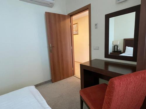 a bedroom with a desk and a mirror and a bed at "Красавиците тъмнокоси" Sunset Resort Pomorie in Pomorie