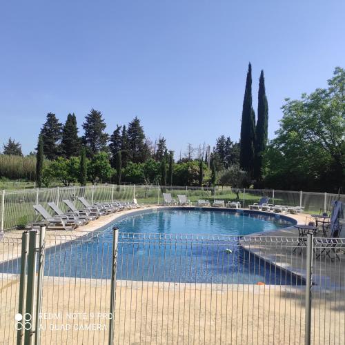 une piscine avec des chaises et une clôture dans l'établissement le Mas de la Jardine, à Velleron
